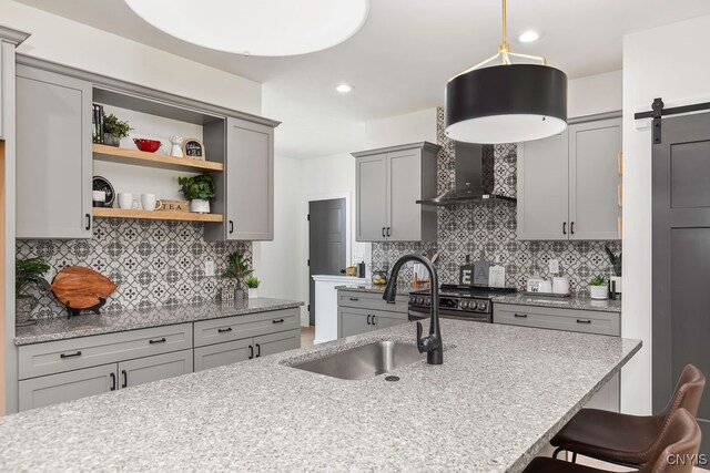 kitchen with gray cabinets, a kitchen bar, backsplash, and a barn door