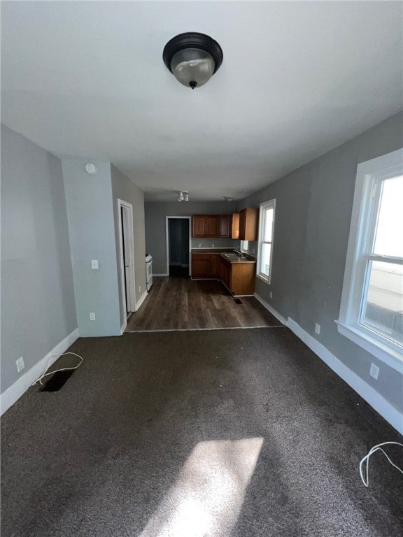 unfurnished living room with dark wood-type flooring and plenty of natural light