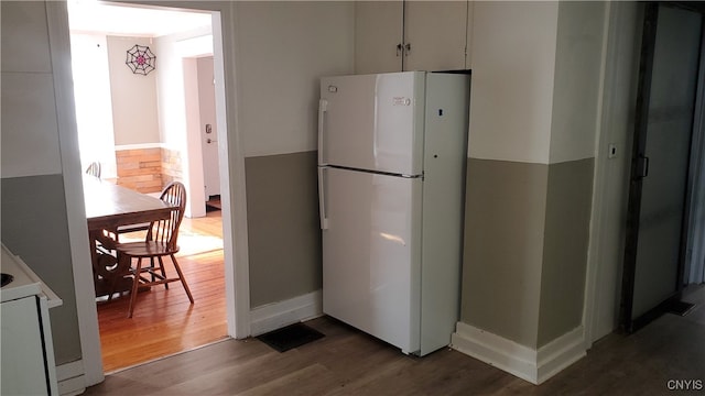 kitchen with white cabinets, dark hardwood / wood-style floors, and white fridge