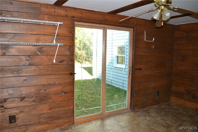 doorway with wooden walls and ceiling fan