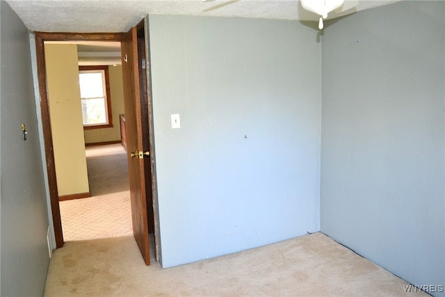 unfurnished room with light carpet, ceiling fan, and a textured ceiling