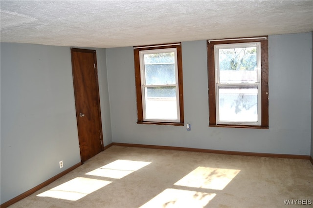 spare room with light colored carpet and a textured ceiling