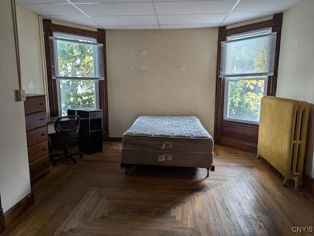 bedroom featuring radiator heating unit and a paneled ceiling