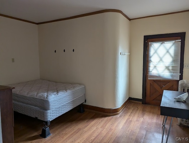 bedroom with crown molding and light hardwood / wood-style floors