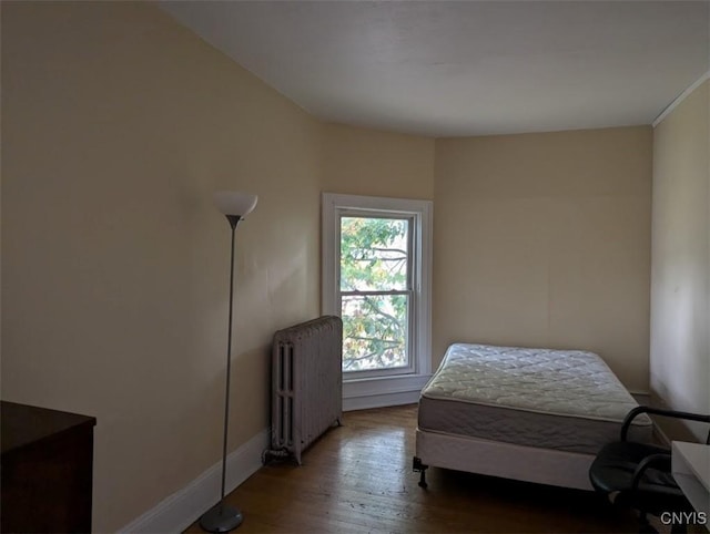 bedroom with baseboards, wood finished floors, and radiator