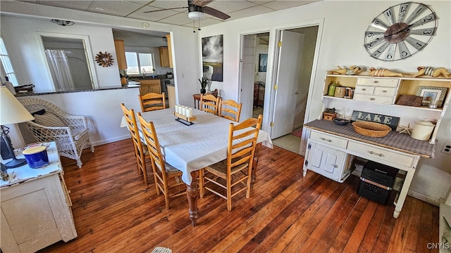 dining area with a drop ceiling, dark hardwood / wood-style floors, sink, and ceiling fan