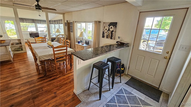 kitchen featuring a healthy amount of sunlight, hardwood / wood-style flooring, a kitchen bar, and ceiling fan