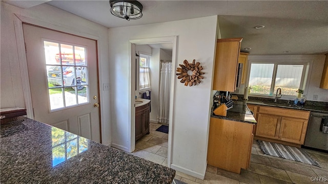 kitchen with dishwasher, dark stone countertops, sink, and plenty of natural light