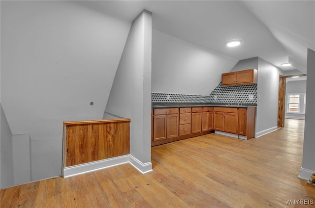 kitchen with vaulted ceiling, backsplash, and light hardwood / wood-style floors