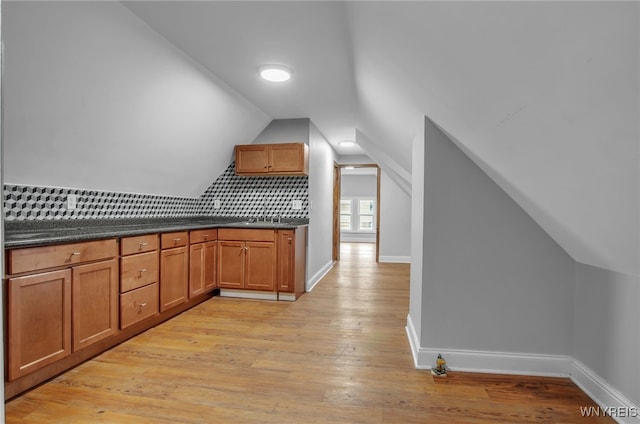 bonus room with sink, light wood-type flooring, and vaulted ceiling