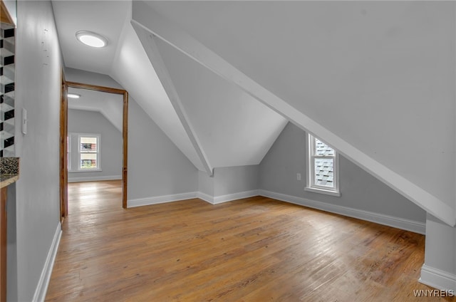 additional living space featuring lofted ceiling, plenty of natural light, and light hardwood / wood-style flooring