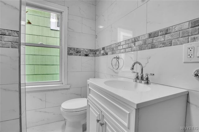 bathroom with toilet, tile walls, and vanity