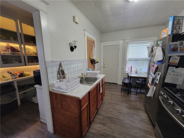 kitchen featuring tasteful backsplash, ornamental molding, dark hardwood / wood-style floors, stainless steel range with gas stovetop, and sink