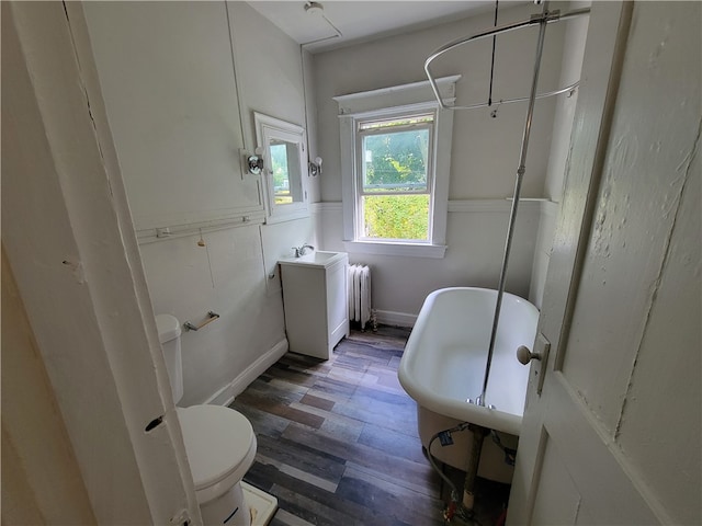 bathroom featuring toilet, hardwood / wood-style flooring, radiator, and a washtub