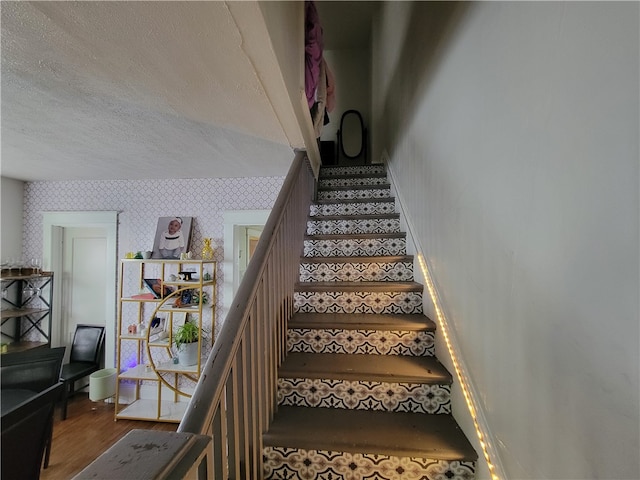 staircase with hardwood / wood-style flooring and a textured ceiling