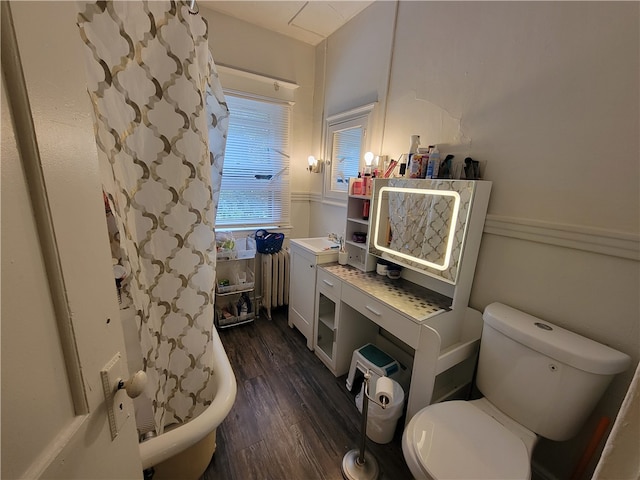 bathroom featuring radiator, toilet, hardwood / wood-style flooring, and a shower with curtain