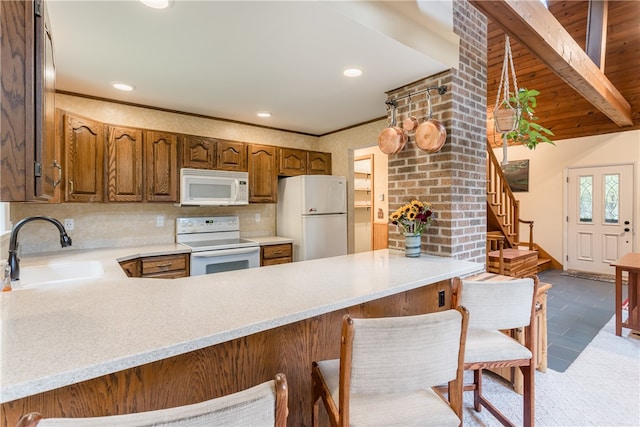 kitchen featuring light tile patterned flooring, sink, a breakfast bar, kitchen peninsula, and white appliances