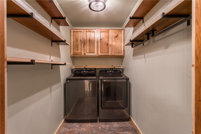 clothes washing area featuring washing machine and dryer and cabinets