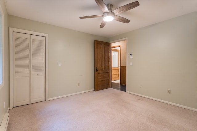 unfurnished bedroom featuring ceiling fan, a closet, a baseboard heating unit, and light colored carpet