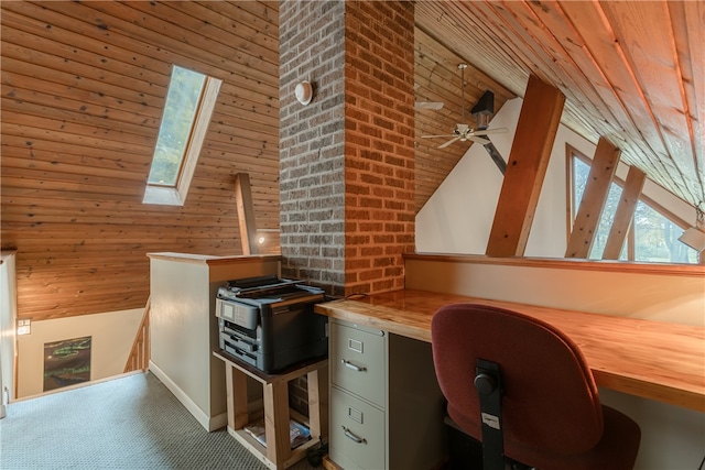 unfurnished office with wooden walls, built in desk, a skylight, and ceiling fan