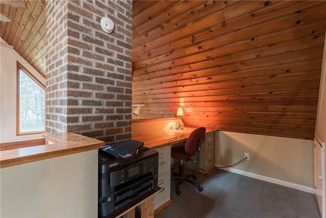 unfurnished office with lofted ceiling, built in desk, and brick wall