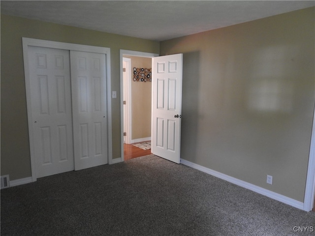 unfurnished bedroom featuring a closet and dark colored carpet