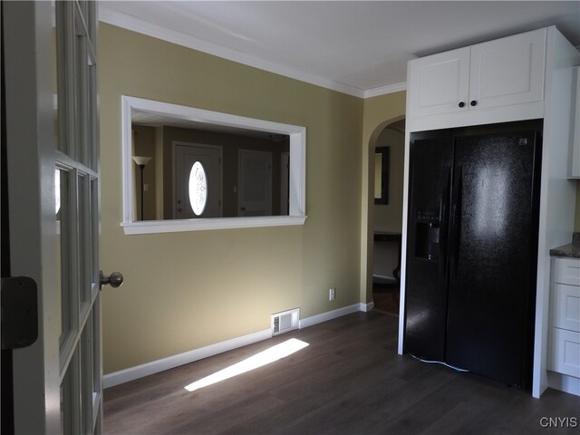 kitchen with dark hardwood / wood-style floors, ornamental molding, black fridge, and white cabinets