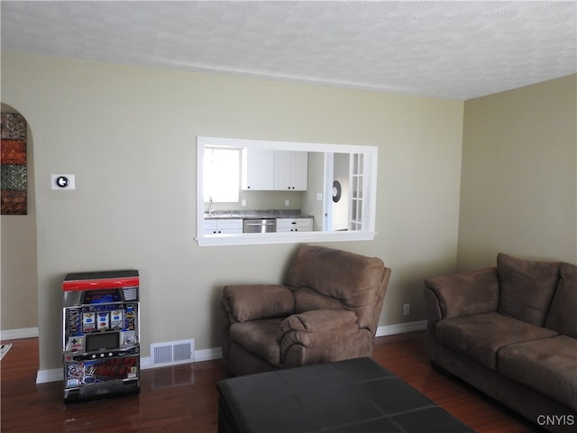 living room with a textured ceiling, sink, and dark hardwood / wood-style floors