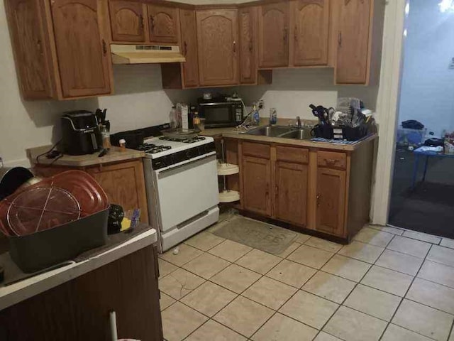 kitchen featuring light tile patterned flooring, gas range gas stove, and sink