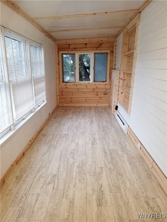 unfurnished room featuring light hardwood / wood-style flooring, wooden walls, and a baseboard heating unit