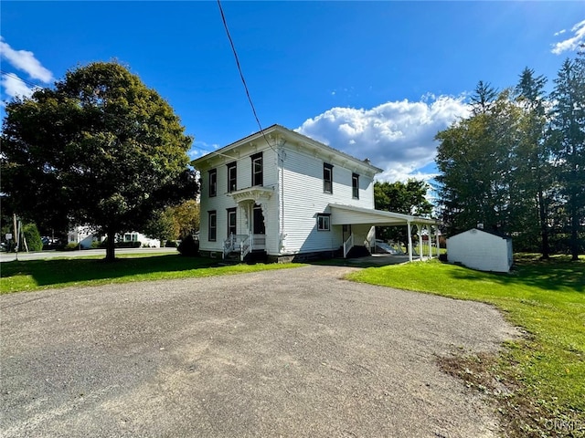 view of side of property with a storage unit, a yard, and a carport