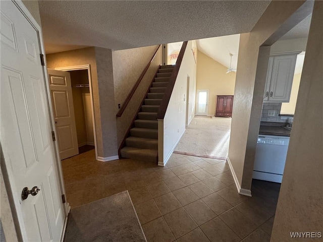 stairs with lofted ceiling, tile patterned flooring, baseboards, and a textured ceiling