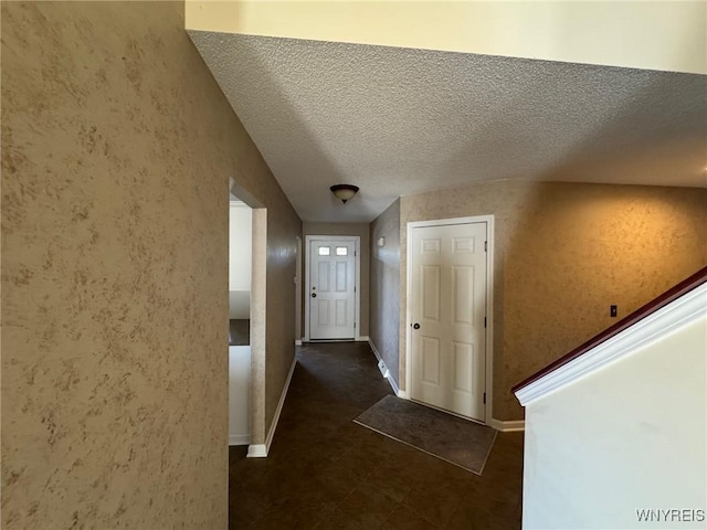 corridor featuring a textured ceiling and baseboards