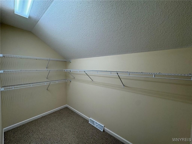 walk in closet featuring carpet floors, visible vents, and vaulted ceiling