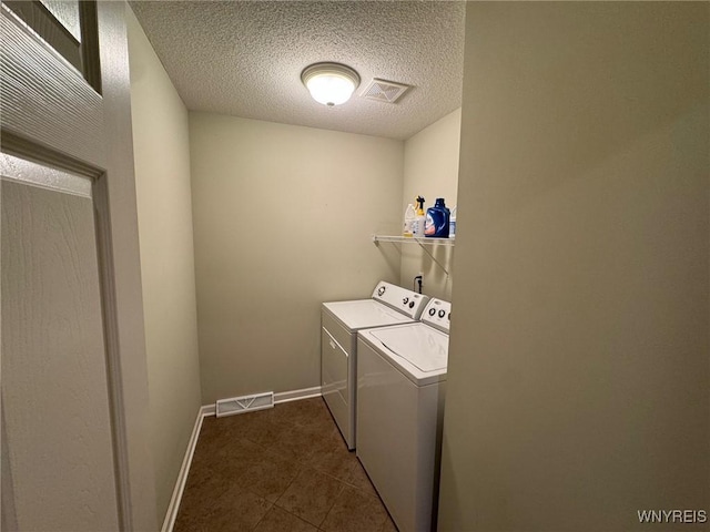 washroom featuring a textured ceiling, laundry area, visible vents, baseboards, and washer and dryer