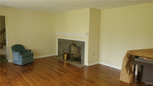 unfurnished living room featuring a stone fireplace and dark wood-type flooring