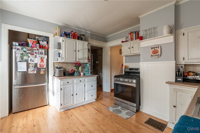 kitchen featuring white cabinets, tasteful backsplash, light wood-type flooring, crown molding, and stainless steel appliances