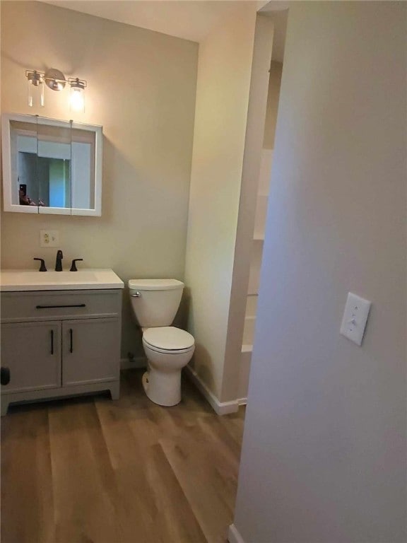 bathroom with toilet, hardwood / wood-style floors, and vanity