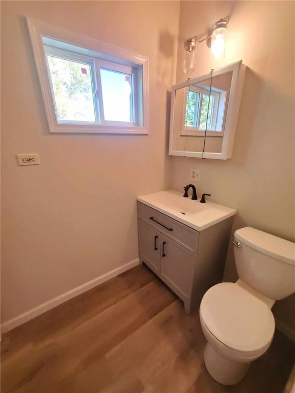 bathroom featuring vanity, toilet, a healthy amount of sunlight, and hardwood / wood-style flooring