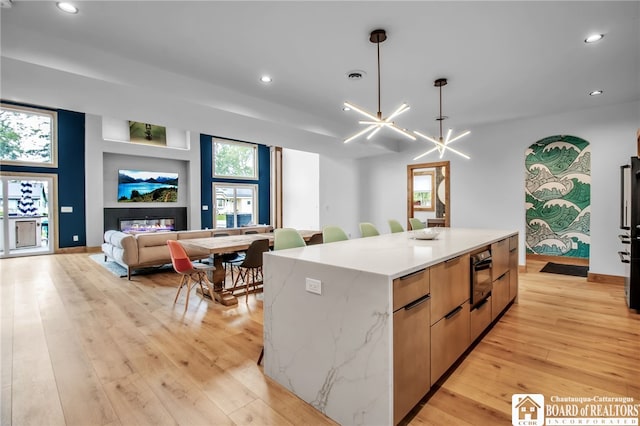 kitchen with a center island, light hardwood / wood-style flooring, pendant lighting, and a chandelier