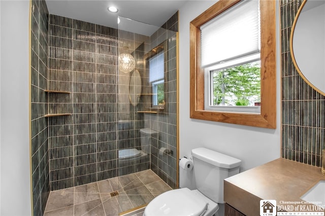 bathroom with vanity, toilet, and tiled shower