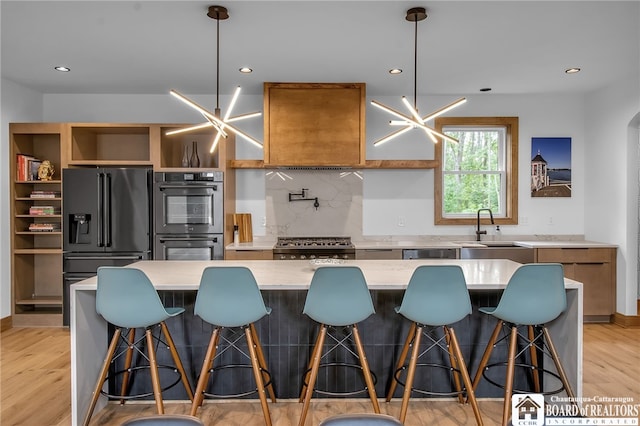 kitchen with sink, appliances with stainless steel finishes, pendant lighting, and an inviting chandelier