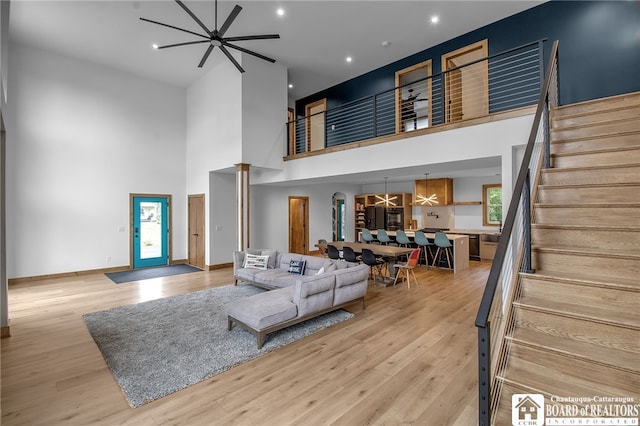 living room with ornate columns, a towering ceiling, light hardwood / wood-style flooring, and ceiling fan