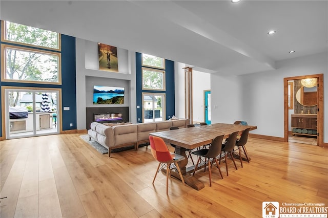 dining space featuring a high ceiling, light wood-type flooring, and decorative columns