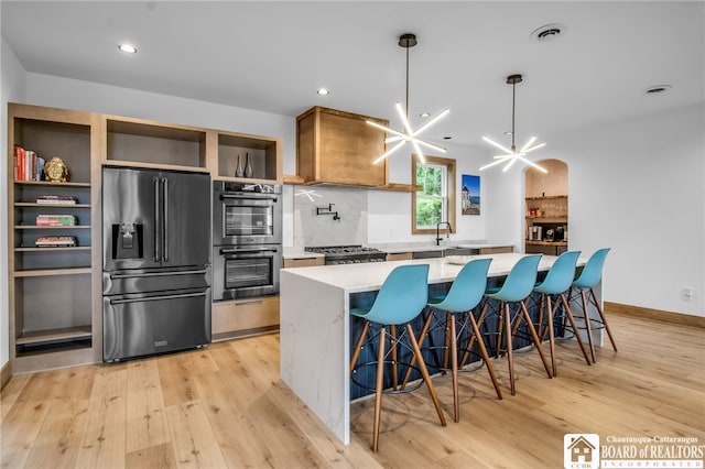 kitchen featuring a breakfast bar, light hardwood / wood-style flooring, a notable chandelier, and stainless steel appliances