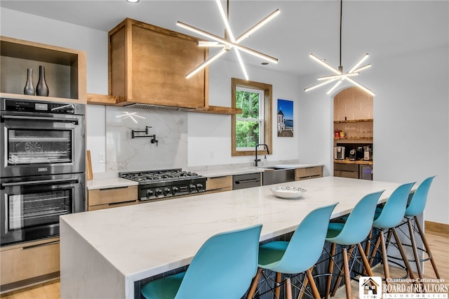 kitchen featuring a kitchen island, a chandelier, stainless steel appliances, and light wood-type flooring