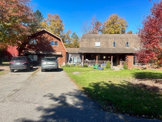 log home with covered porch, a front yard, and a garage