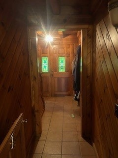 hallway with wood walls and light tile patterned floors