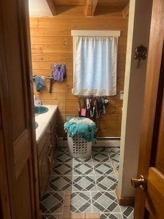 bathroom featuring vanity, wood walls, tile patterned floors, and a baseboard heating unit