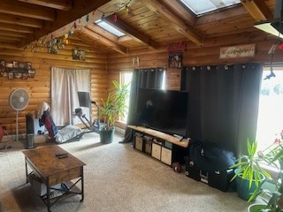 living room featuring vaulted ceiling with skylight, carpet, wooden ceiling, and rustic walls